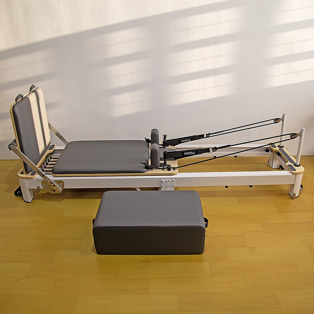 Folding Pilates reformer machine for full-body fitness, featuring adjustable straps and padded carriage for home workouts.