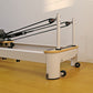 Folding Pilates reformer machine with adjustable straps and padded platform for full body fitness exercises at home.