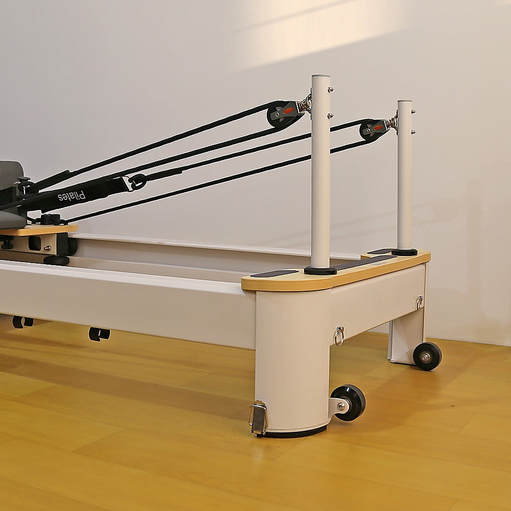 Folding Pilates reformer machine with adjustable straps and padded platform for full body fitness exercises at home.
